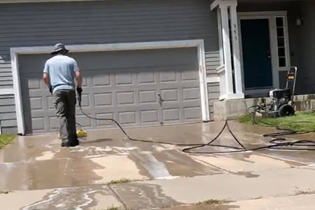 Technician pressure washing a concrete driveway in northern colorado co